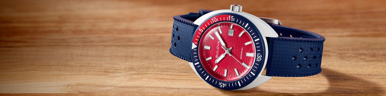 New Arrival Watches; Featuring an image of Snorkel Sail 4th watch model 98B474 on a wood tabletop background