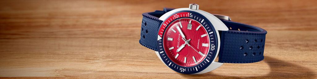 New Arrival Watches; Featuring an image of Snorkel Sail 4th watch model 98B474 on a wood tabletop background
