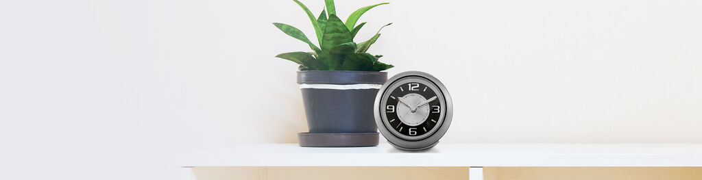 Alarm Clock Next to Plant on Table