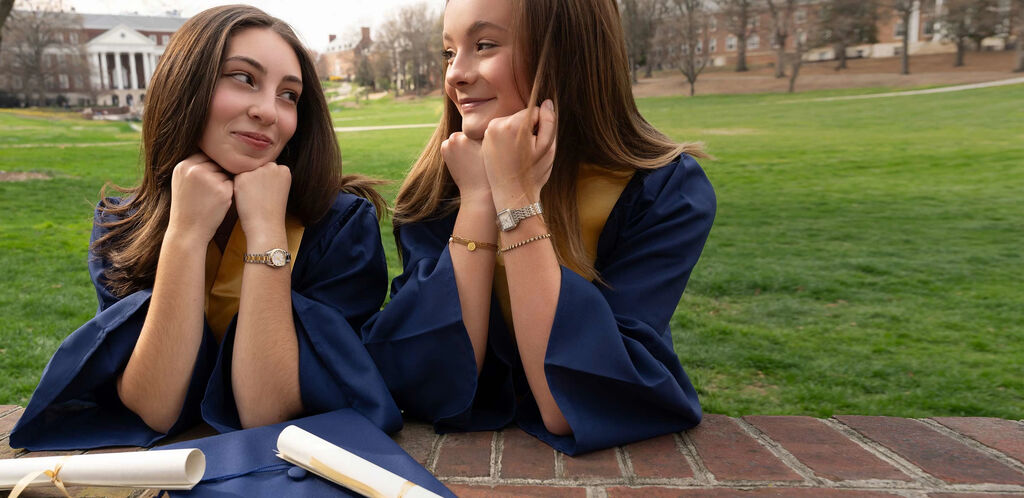 Graduation Gift Guide; Image of two women in their graduation caps and gowns wearing Sutton and Surveyor watch models 96R256 and 98L331